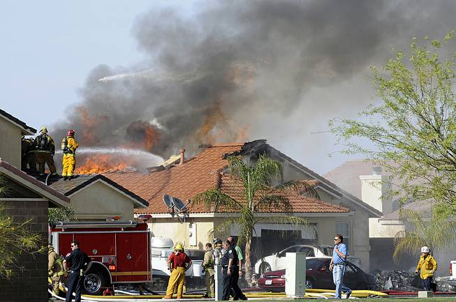 This photo shows the site of a military jet that crashed on a residential street in Imperial, Calif., setting two homes on fire Wednesday, June 4, 2014. Lance Cpl. Christopher Johns, a U.S. Marines spokesman, says the jet was a Harrier from Marine Corps Air Station in Yuma, Ariz. 