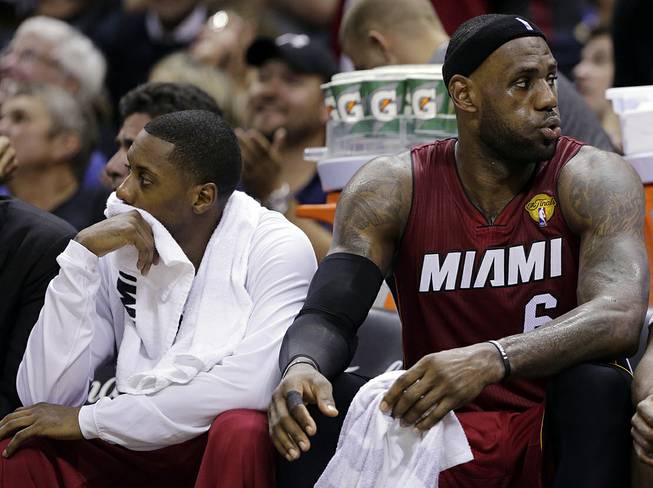 Miami Heat guard Mario Chalmers, left, and forward LeBron James watch action against the San Antonio Spurs from the bench during the second half in Game 1 of the NBA basketball finals on Thursday, June 5, 2014 in San Antonio. 