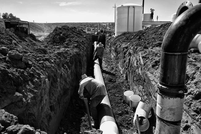 Workers install pipe to a new well in Huron, California. During the season the areas farms need the most labor the work force doubles, but a drought has cut production and workers find trouble landing positions in the fields.