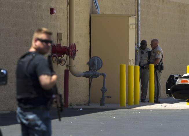 A Nevada Highway Patrol trooper, left, and Metro Police officers cover a Wal-Mart back door on Nellis Boulevard on Sunday, June 8, 2014. Two suspects allegedly shot two Metro Police officers in a nearby pizza shop, then fled to the Wal-Mart, where they fired shots before killing themselves.