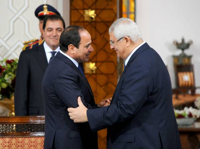 In this photo provided by Egypt's state news agency MENA, Egyptian President Abdel-Fattah el-Sissi, left, and interim President Adly Mansour shake hands after signing a "handover of power document," transferring the presidency to el-Sissi in the presence of dozens of local and foreign dignitaries at the presidential palace in Cairo, Egypt, on Sunday, June 8, 2014. Egypt's newly sworn-in president called on his country Sunday to build a more stable future after years of turmoil and revolt, asking them to work hard so that their rights and freedoms could grow. Retired Field Marshal el-Sissi, the former military chief who ousted Egypt's first freely elected leader last July, addressed a ceremony held at a presidential palace in Cairo hours after he was sworn in by the Supreme Constitutional Court.