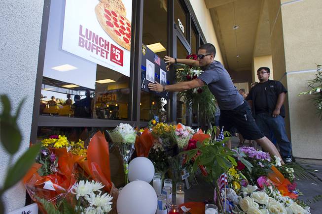 Anthony Gariano puts up a sign at a memorial in front of CiCi's Pizza shop, where two Metro Police officers were killed, during a community vigil Monday, June 9, 2014. Police officers Alyn Beck, 41, and Igor Soldo, 31, were ambushed and killed in the restaurant while they were eating lunch on June 8.