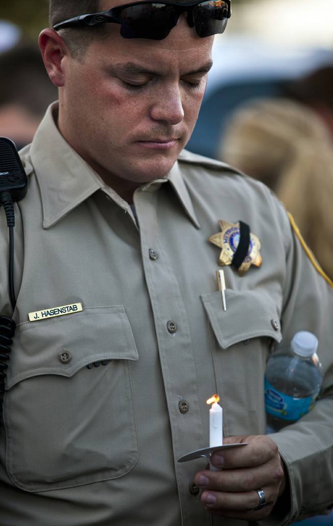 Metro Police officer J. Hasenstab bows his head with lit candle during a candlelight vigil to show support for slain officers Alyn Beck and Igor Soldo outside of CiCi's Pizza restaurant on Monday, June 9, 2014.