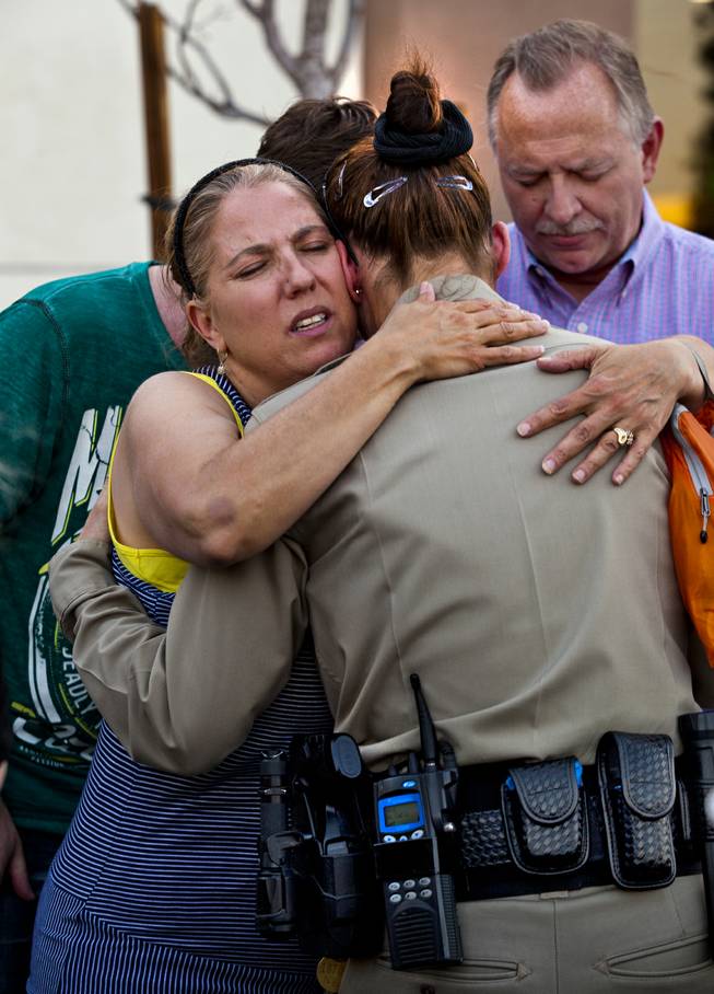 Cheri Rasmussen with the International Church of Las Vegas hugs Metro Police officer T. Bonner following a candlelight vigil outside of CiCi's Pizza restaurant to honor slain officers Alyn Beck and Igor Soldo on Monday, June 9, 2014.  They are joined by Ryan and Mark Rasmussen.