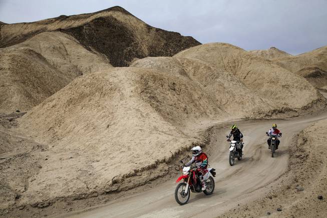 On a Honda CRF250L, Mark Buche, followed by Ty van Hooydonk on a Kawasaki KLX250, followed by a Suzuki DR-Z400S piloted by jun Villegas, the trio rides through Twenty Mule Team Canyon, located in the Furnace Creek area of Death Valley, a one way 2.7 mile loop and the road is unpaved, April 18, 2014.