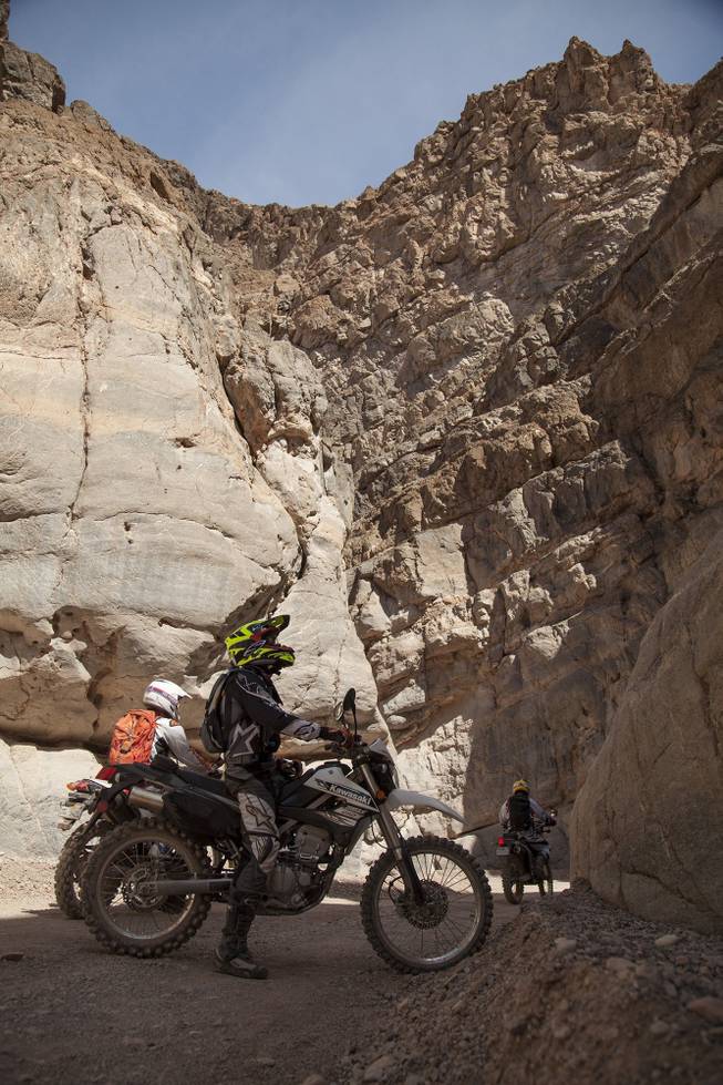 Ty van Hooydonk, stops on his Kawasaki KLX250S to look at the beauty of Titus Canyon Narrow on a recent visit to Death Valley National Park. Jun Villegas, aboard a Suzuki DR-Z400S continues desert journey with Mark Buche, on a Honda CRF250L following.