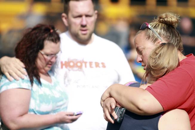 People comfort each other as they await word about the safety of students after a shooting at Reynolds High School Tuesday, June 10, 2014, in Troutdale, Ore. A gunman killed a student at the high school east of Portland Tuesday and the shooter is also dead, police said.