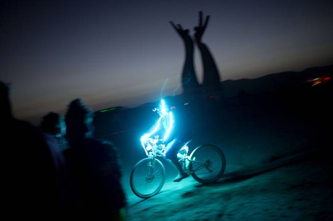In this photo taken Thursday, June 5, 2014, an Israeli man rides a bicycle as the sun goes down during Israelis first Midburn festival in the desert near the Israeli kibbutz of Sde Boker.