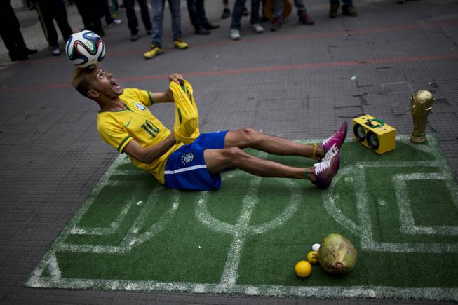 A street performer dressed as a Brazilian national soccer team player, balances a ball on his head during his presentation in downtown Sao Paulo, Brazil, Tuesday, June 10, 2014. The 2014 World Cup is set to begin Thursday, with Brazil and Croatia competing in the opening match in Sao Paulo.