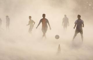 Aspiring young Indian soccer players continue with their practice during a dust storm in Jammu, India, Wednesday, June 11, 2014. Soccer fans around the world are gearing up to watch the Soccer World Cup that begins in Brazil Thursday. 