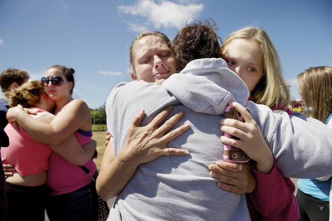 Brandi Wilson, left, and her daughter, Trisha Wilson, 15, right, embrace Trish Hall, a mother waiting for her student, as students arrived at the Fred Meyer grocery store parking lot in Wood Village, Ore., after a shooting at Reynolds High School Tuesday, June 10, 2014, in nearby Troutdale.