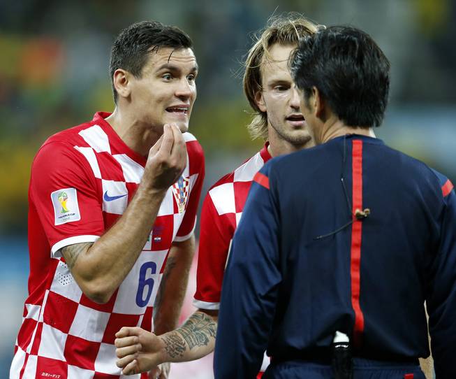 Croatia's Dejan Lovren, left, and teammate Ivan Rakitic, center, complain to referee Yuichi Nishimura, from Japan, after Nishimura issued a penalty against Croatia during the group A World Cup soccer match between Brazil and Croatia in the opening game of the tournament at Itaquerao Stadium in Sao Paulo, Brazil, Thursday, June 12, 2014.