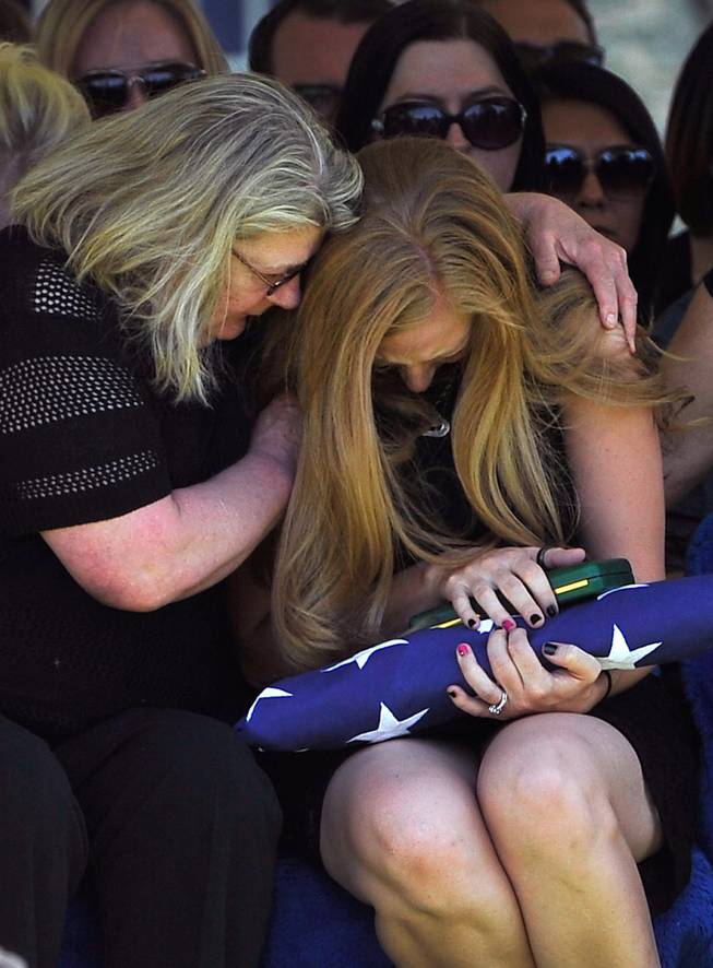 Andrea Soldo is consoled by a family member after receiving a flag during the funeral services for her husband and Las Vegas police officer Igor Soldo at Palm Northwest Mortuary & Cemetery on Thursday, June 12, 2014 in Las Vegas. Soldo, 31, and fellow officer, Alyn Beck, 41, were gun down by two assailants at a Cici's Pizza during their lunch break Sunday. Services for Beck are scheduled for Saturday. 