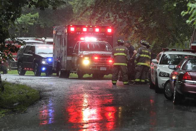 Emergency vehicles and personnel stand near a command post set up for a small plane that crashed on a road just west of Westchester County Airport, Friday, June 13, 2014, in Purchase, N.Y. The single-engine plane took off just after 8 a.m. and went down after hitting some trees, killing Richard Rockefeller, a great grandson of Standard Oil co-founder John D. Rockefeller. 