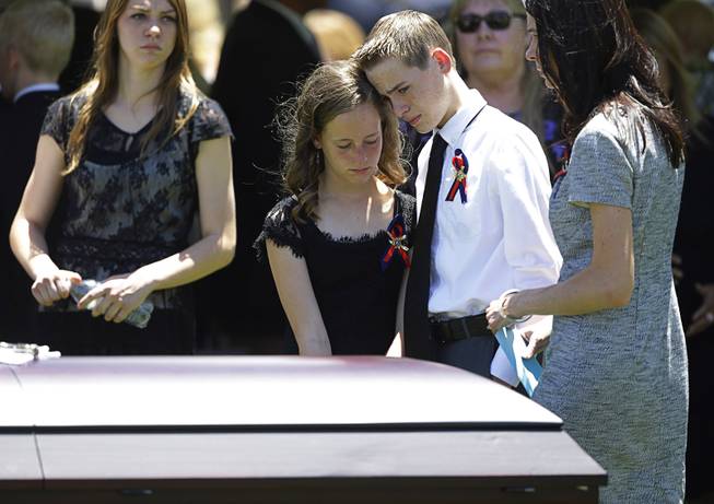Daxton Beck, center right, leans his head on his sister Avenlee Beck as they stand over the casket of their father Las Vegas Metropolitan Police Officer Alyn Beck during a memorial at The Smith Center for the Performing Arts Saturday, June 14, 2014 in Las Vegas. Two suspects shot and killed Beck, 41, and fellow police officer Igor Soldo, 31, in an ambush at a Las Vegas restaurant Sunday, June 8, 2014, before fatally shooting a third person inside a nearby Wal-Mart, authorities said.