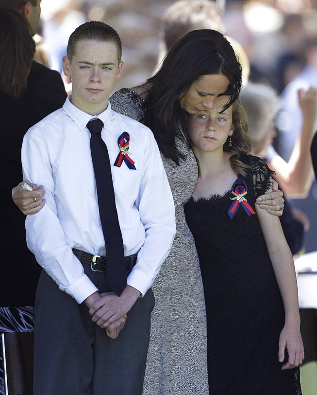 Nicole Beck, center, comforts her children Daxton Beck, left, and Avenlee Beck at a memorial for Nicole Beck's husband and the children's father Las Vegas Metropolitan Police Officer Alyn Beck at The Smith Center for the Performing Arts Saturday, June 14, 2014 in Las Vegas. Two suspects shot and killed Beck, 41, and fellow police officer Igor Soldo, 31, in an ambush at a Las Vegas restaurant Sunday, June 8, 2014, before fatally shooting a third person inside a nearby Wal-Mart, authorities said.