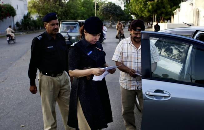Pakistani female police officer Syeda Ghazala checks documents of a vehicle in Karachi, Pakistan. Just days into her job running a police station in Pakistan's largest city, Syeda Ghazala had to put her training to the test: she opened fire with her .22-caliber pistol at a man who shot at police when they tried to pull him over during a routine traffic stop.