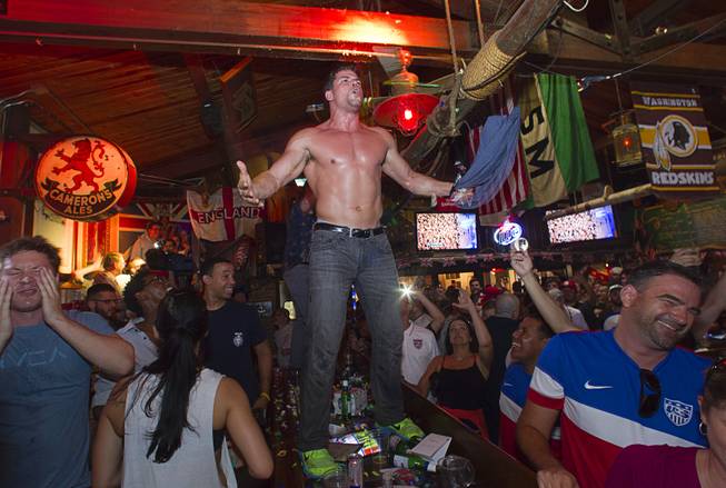 A soccer fan celebrates on a bar after watching the United States beat Ghana 2-1 in the World Cup during a viewing party at the Crown & Anchor British Pub Monday, June 16, 2014.