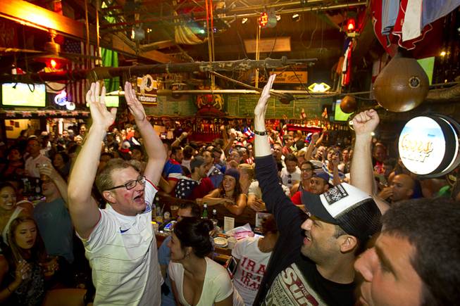 Aaron Kemper, left,  and other soccer fans celebrate after the United States makes their first goal against Ghana in the World Cup during a viewing party at the Crown & Anchor British Pub Monday, June 16, 2014.