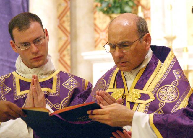In this photo provided by The Catholic Sun, date not known, the Rev. Kenneth Walker, left, and the Rev. Joseph Terra perform a Mass in Phoenix. Walker was killed and Terra was critically injured during a robbery attempt at Mater Misericordiae Mission on Wednesday, June 11, 2014.