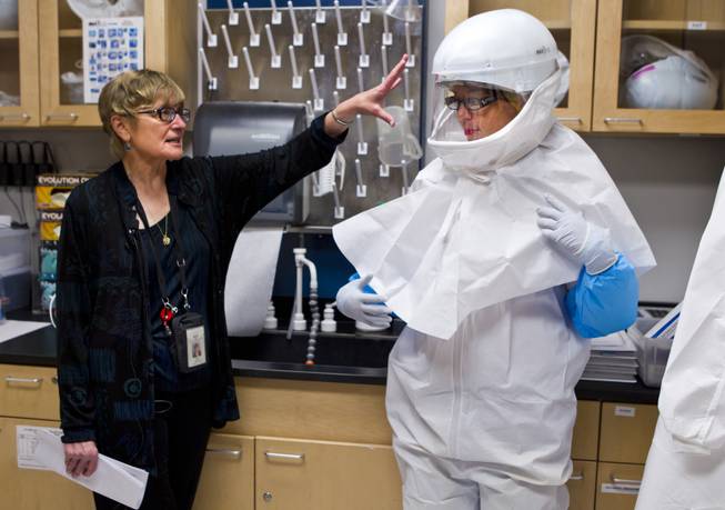 Southern Nevada Public Health Laboratory manager Patricia Armour describes the safety features of full Personal Protective Equipment (PPE) worn by lab assistant Betsy Sapp for the BSL-3 laboratory on Wednesday, June 11, 2014.