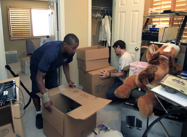 Eric Crockett and Jeff Lenning with Southern Nevada Movers work to pack up the household goods of the Delmundo family Monday, June 16, 2014.