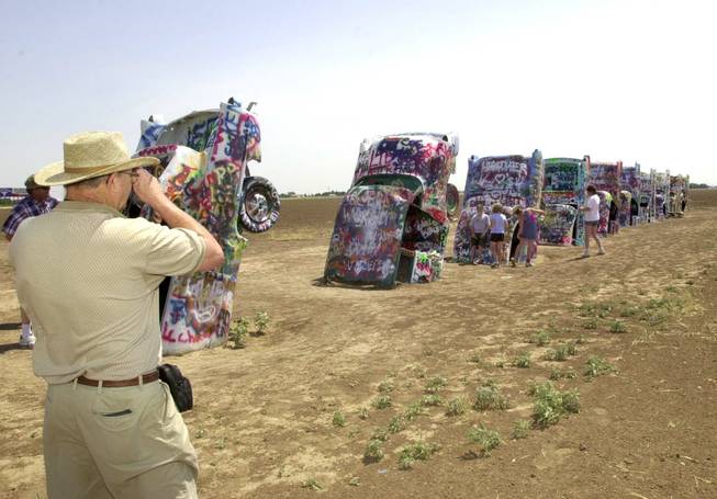 Donald Benton, left, photographs members of his family during a stop at the Cadillac Ranch just west of Amarillo, Texas, June 18, 2002.