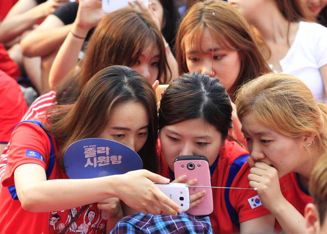 South Korean soccer fans use their smartphones to watch a live broadcast of the group H World Cup soccer match between Russia and South Korea as the screen was turned off due to a network error at a public viewing venue in Seoul, South Korea, Wednesday, June 18, 2014.(AP Photo/Ahn Young-joon)