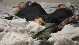 Detainees sleep in a holding cell at a U.S. Customs and Border Protection processing facility, Wednesday, June 18, 2014, in Brownsville,Texas. CPB provided media tours Wednesday of two locations in Brownsville and Nogales, Ariz., that have been central to processing the more than 47,000 unaccompanied children who have entered the country illegally since Oct. 1.  (AP Photo/Eric Gay, Pool)