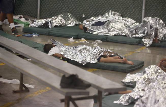 Young boys sleep in a holding cell where hundreds of mostly Central American immigrant children are being processed and held at the U.S. Customs and Border Protection Nogales Placement Center on Wednesday, June 18, 2014, in Nogales, Ariz.