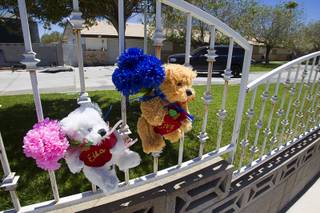 Stuffed bears with the names of Ella and Cruz Flores are posted on a fence after an early morning fire at the home near Ann Road and Durango Drive Thursday, June 19, 2014. The children, ages 2 and 4-years-old, died in the fire.
