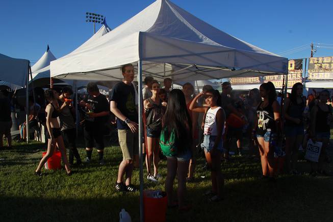 Attendees seek relief from the heat under a tent during the Las Vegas stop of the Vans Warped Tour Thursday, June 19, 2014.