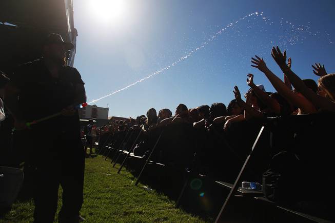 A security guard sprays ice water on fans waiting for a band to start during the Las Vegas stop of the Vans Warped Tour Thursday, June 19, 2014.