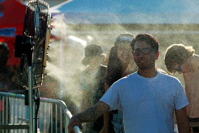 Attendees stand in misters to cool off during the Las Vegas stop of the Vans Warped Tour Thursday, June 19, 2014.