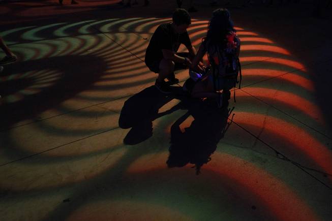 A couple crouches in a pool of light during the first night of the Electric Daisy Carnival Saturday, June 21, 2014 at the Las Vegas Motor Speedway.