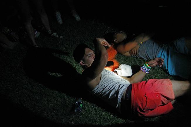 A beam from a security guard's flashlight awakens a sleeping person during the first night of the Electric Daisy Carnival early Saturday, June 21, 2014 at the Las Vegas Motor Speedway.