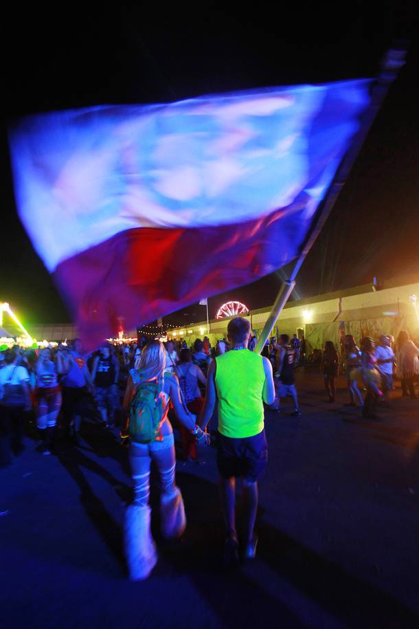 A couple carry a large flag during the first night of the Electric Daisy Carnival early Saturday, June 21, 2014 at the Las Vegas Motor Speedway.