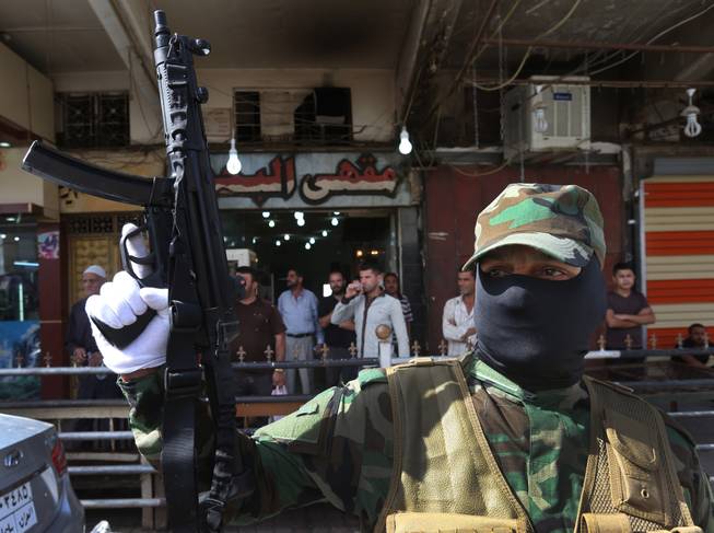 An Iraqi Shiite masked militiaman, a follower of Shiite cleric Muqtada al-Sadr, holds up his machine gun during a parade in the northern oil rich province of Kirkuk, Iraq, on Saturday, June 21, 2014. Thousands of heavily-armed Shiite militiamen paraded through several Iraqi cities on Saturday as Sunni militants seized two strategically located towns in what appeared to be a new offensive in the western Anbar province.