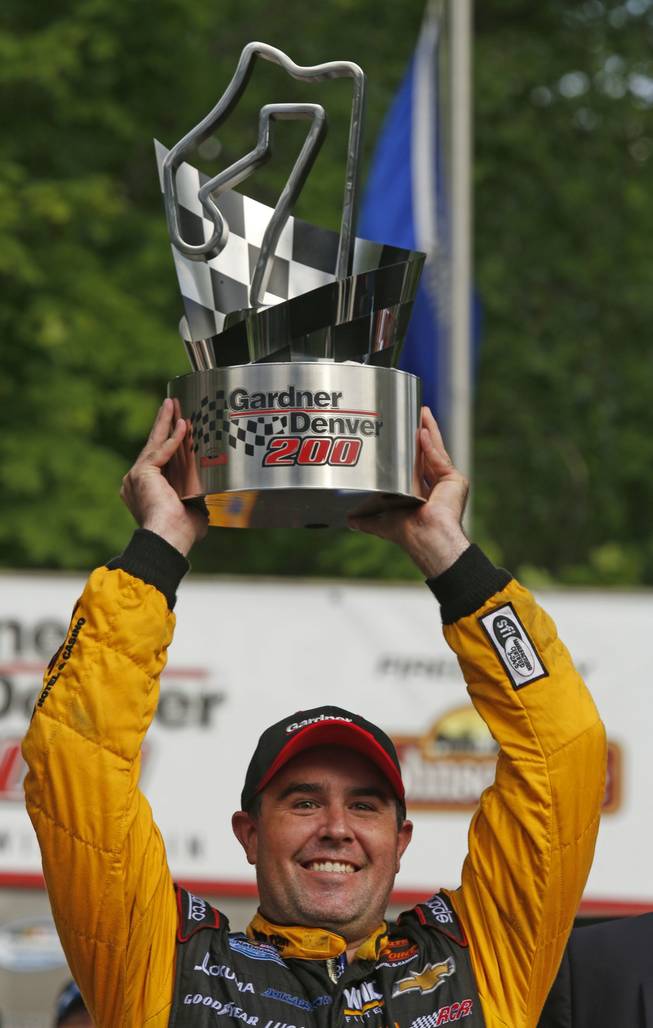 Brendan Gaughan lifts the trophy in Victory Lane after winning the NASCAR Nationwide series race at Road America in Elkhart Lake, Wis., on Saturday, June, 21, 2014.