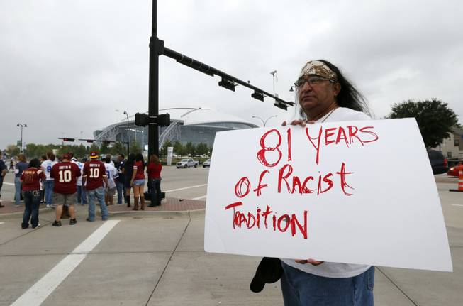 In this Oct. 13, 2014, file photo, Juan Mancias, of Floresville, Texas, a member of the American Indian Movement of Central Texas, holds a sign as he joins others in protest before an NFL football game between the Washington Redskins and Dallas Cowboys in Arlington, Texas. The U.S. Patent Office ruled Wednesday, June 18, 2014, that the Washington Redskins nickname is "disparaging of Native Americans" and that the team's federal trademarks for the name must be canceled.