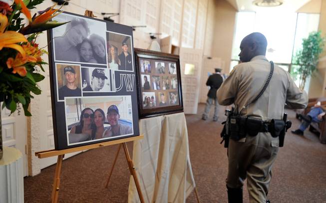 A Las Vegas police officer looks at a poster of photographs of Joseph Wilcox before a memorial service at Palm Downtown Mortuary and Cemetery on Sunday, June 22, 2014. Wilcox, 31, was killed trying to stop Jerad and Amanda Miller in the midst of their shooting spree at an east valley Walmart store on June 8.