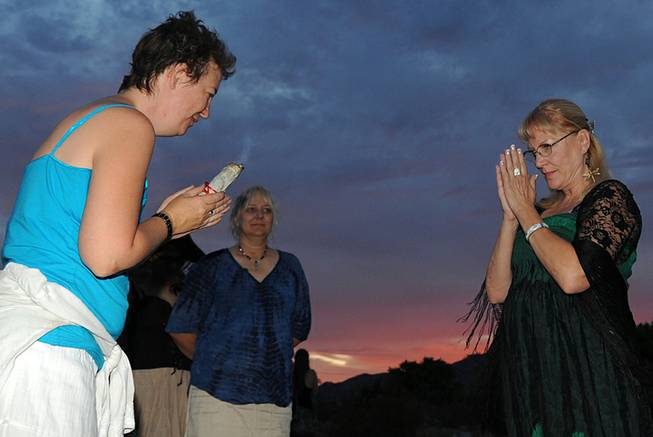 Priestess in training Melissa Ameika, left, bows to Sherry Watts after smudging her with sage, blessing her before she crosses a bridge leading to a small temple during a Wiccan celebration of Litha, honoring the summer solstice on Saturday evening in the desert near Indian Springs.
