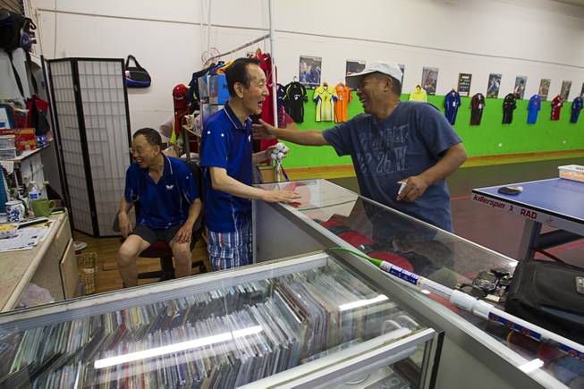 Jong Jin Lee, center, 73, talks with Percy Mariano about the price of paddles at the Nevada Table Tennis Center, 4063 Renate Dr. (Chinatown Mall), Wednesday, June 25, 2014. Sam Lee, left, 64, takes break to watch World Cup soccer on a television.