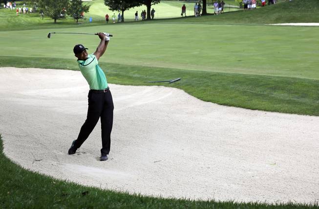 Tiger Woods chips out of a sand trap on the ninth fairway during the first round of the Quicken Loans National PGA golf tournament, Thursday, June 26, 2014, in Bethesda, Md.