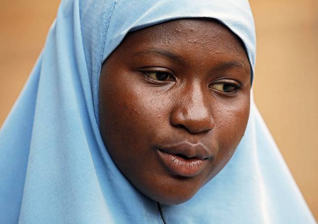 In this Sunday, June 1, 2014 photo, Maimuna Abdullahi sits outside her school in Kaduna, Nigeria. Maimuna wore the scars of an abused woman anywhere: A swollen face, a starved body, and, barely a year after her wedding, a divorce. 