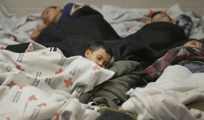 This June 18, 2014, file photo shows children detainees sleeping in a holding cell at a U.S. Customs and Border Protection processing facility in Brownsville, Texas. 