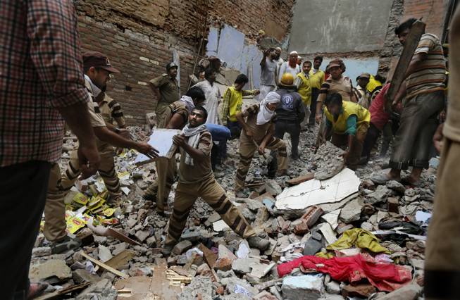 Rescue workers clear debris at the site of a building collapse in New Delhi, India, on Saturday, June 28, 2014. A dilapidated building collapsed in the Indian capital, killing at least 15 people.