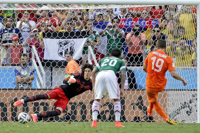 Mexico's goalkeeper Guillermo Ochoa can not stop a penalty shot by Netherlands' Klaas-Jan Huntelaar to score his side's second and winning goal during the World Cup round of 16 soccer match between the Netherlands and Mexico at the Arena Castelao in Fortaleza, Brazil, Sunday, June 29, 2014. The Netherlands defeated Mexico 2-1. (AP Photo/