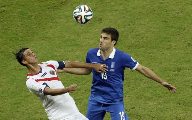 Costa Rica's Bryan Ruiz, left, and Greece's Sokratis Papastathopoulos challenge for the ball during the World Cup round of 16 soccer match between Costa Rica and Greece at the Arena Pernambuco in Recife, Brazil, on Sunday, June 29, 2014.