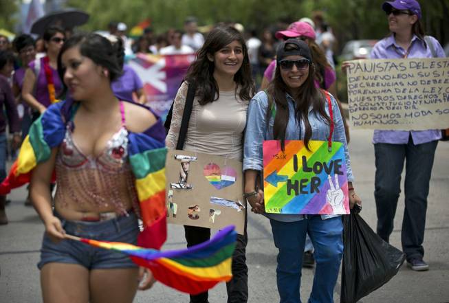 A young lesbian couple wears signs proclaiming their love as they walk in Mexico City's annual gay pride parade Saturday, June 28, 2014. Thousands of people supporting the rights of gays, lesbians, bisexuals and transgenders marched through the streets of central Mexico City Saturday, many waving rainbow flags or wearing intricate costumes. Gay marriage is legal within Mexico City. Gays, lesbians, bisexuals and transgenders are holding gay pride parades worldwide this month as part of annual demonstrations demanding equal rights and to protest discrimination.